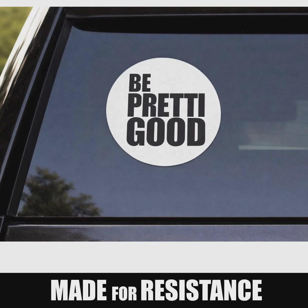 May include: A white circular sticker with the words "BE PRETTI GOOD" in bold, black capital letters. The sticker is affixed to a car window. Below the sticker, the text "MADE FOR RESISTANCE" is displayed in white capital letters.