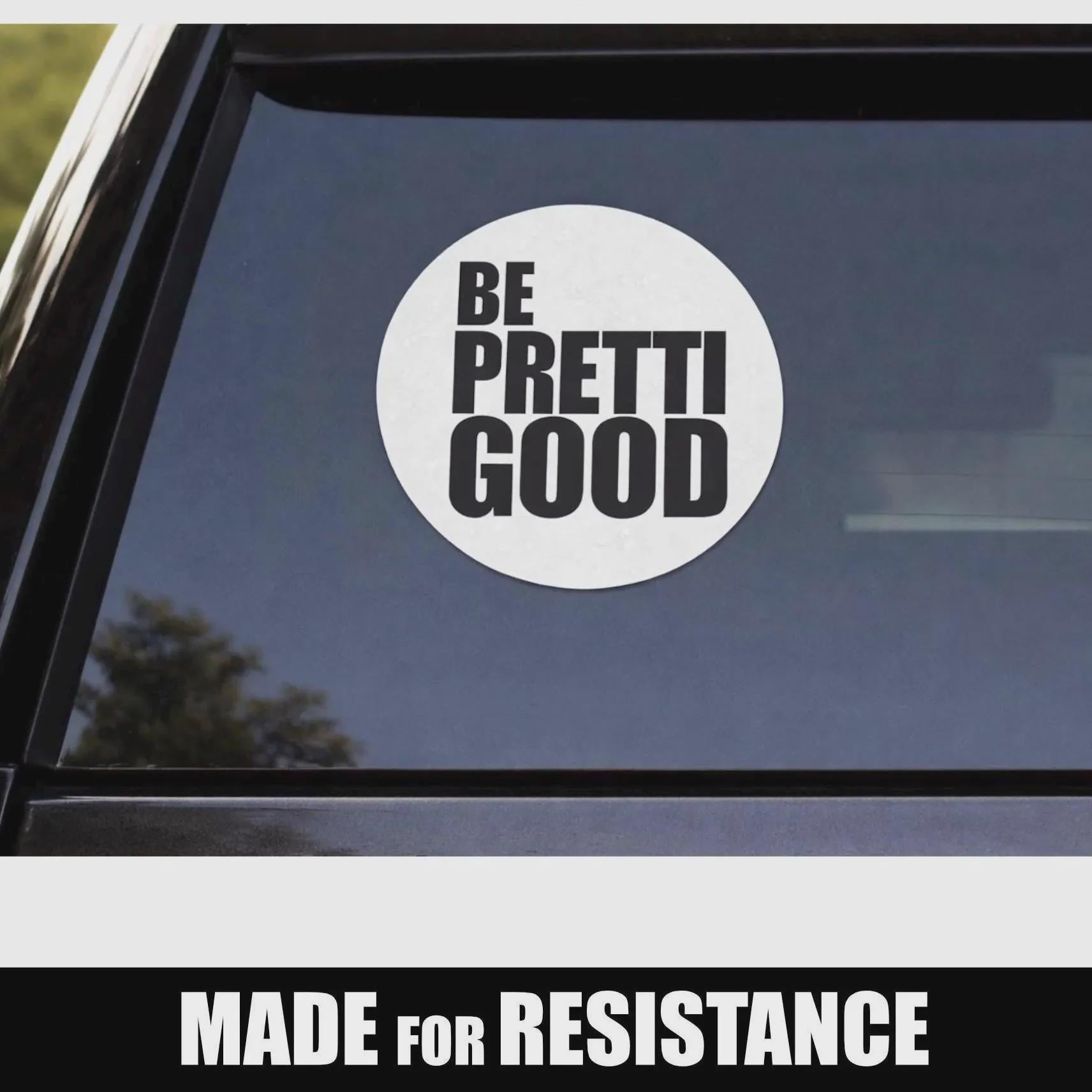 May include: A white circular sticker with the words "BE PRETTI GOOD" in bold, black capital letters. The sticker is affixed to a car window. Below the sticker, the text "MADE FOR RESISTANCE" is displayed in white capital letters.