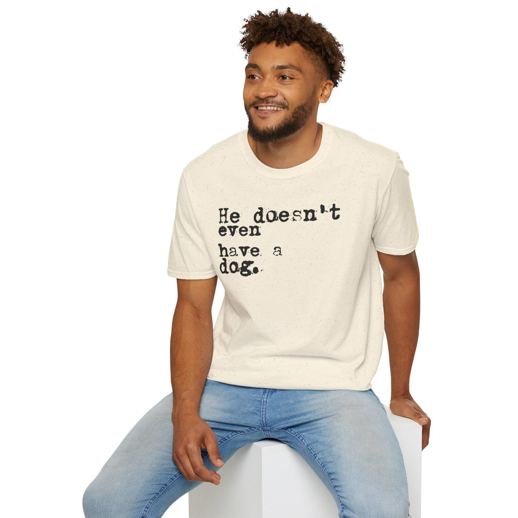 May include: Cream-colored t-shirt with the text "He doesn't even have a dog." printed in black. The shirt is short-sleeved and has a crew neck. The person is wearing blue jeans.