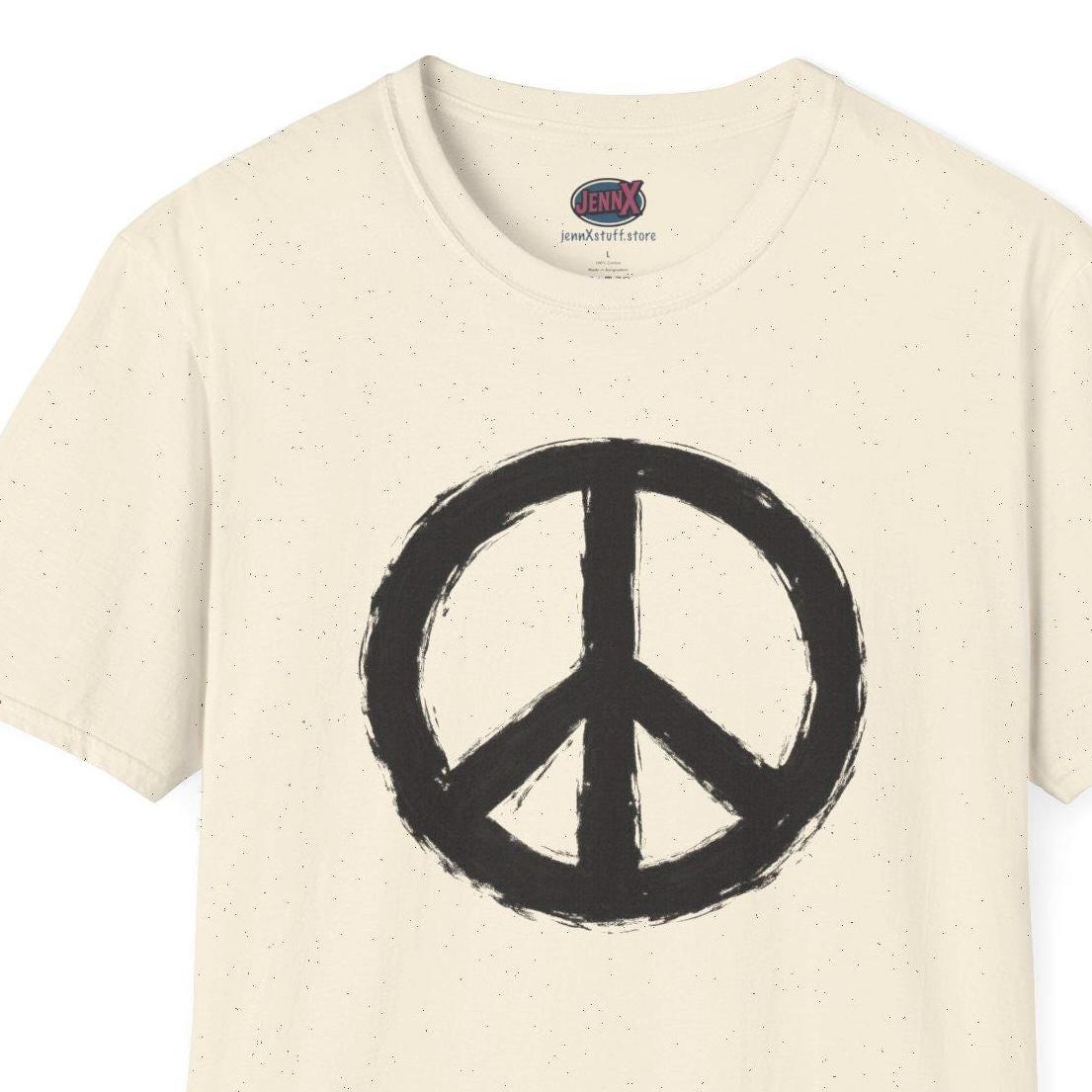 May include: Cream-colored t-shirt featuring a large, distressed black peace symbol. The short-sleeved shirt has a crew neck and a simple, casual design. The peace sign is centered on the front of the shirt.