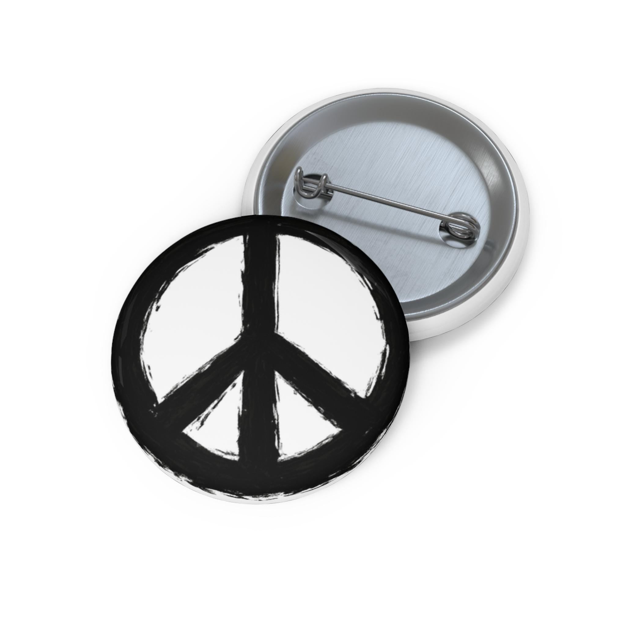 May include: Two round, white and black peace sign buttons. One button is face up, displaying a black peace symbol on a white background. The other button is face down, showing the pin back.